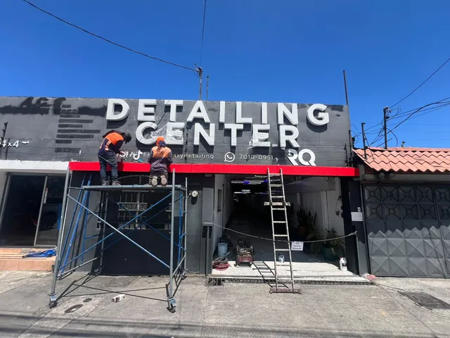 Fachada del Detailing Center con rótulo negro y andamios