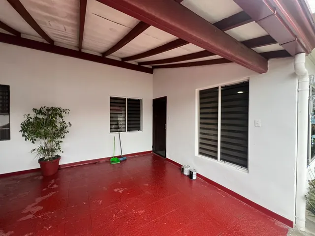 Corredor de casa con paredes blancas, vigas y piso rojo terminados