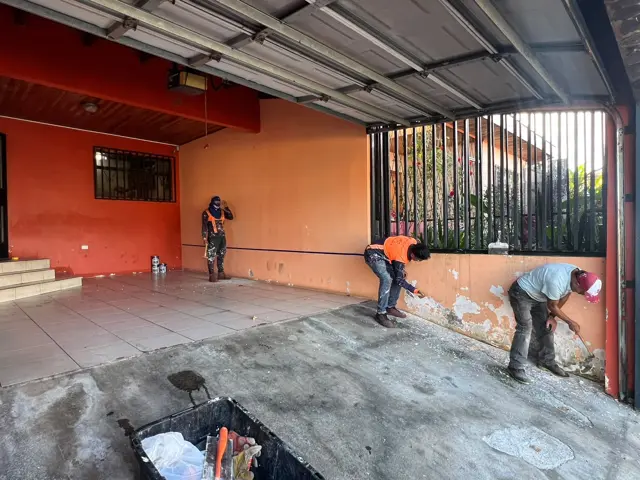 Técnicos tratando la humedad en la base de los muros de una cochera