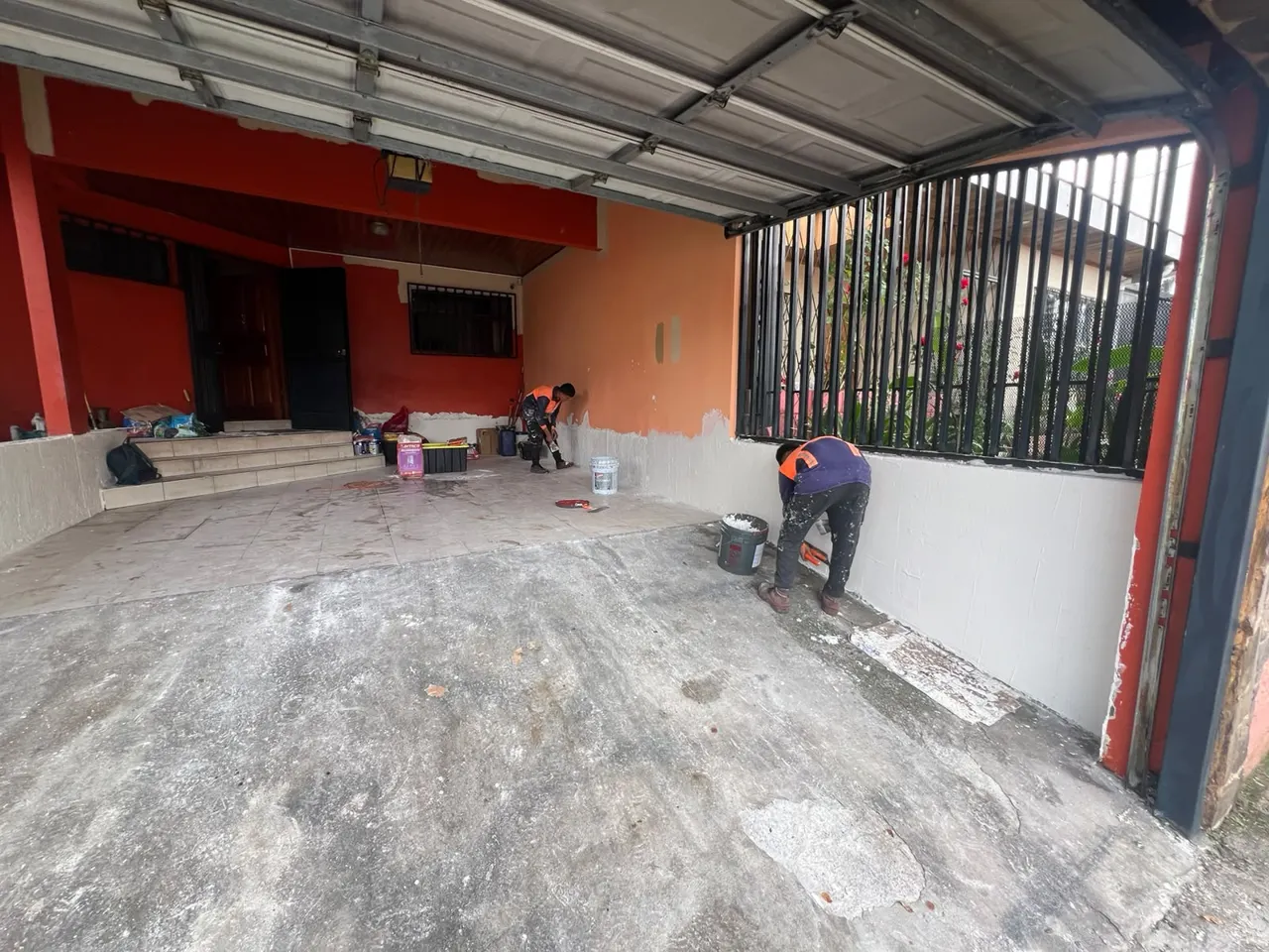 Muro tratado con base blanca y técnicos trabajando en la cochera